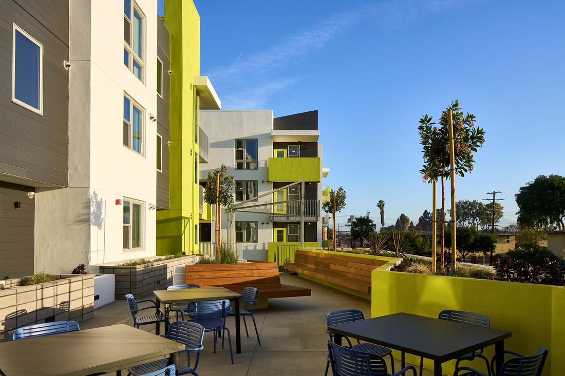 a patio with tables and chairs next to a building.