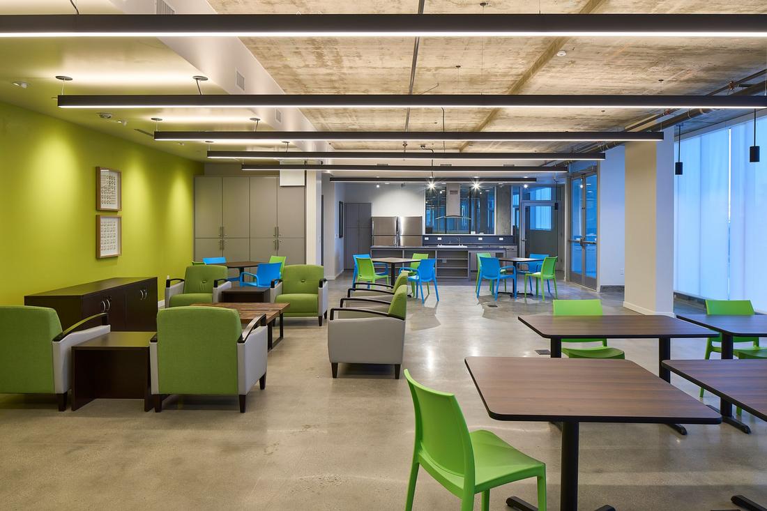 a room with tables, chairs, and a bar.