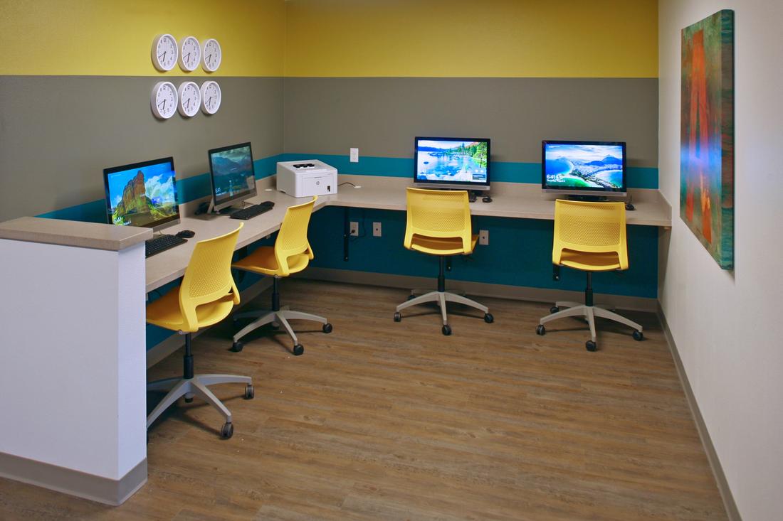 a room with three computers and three yellow chairs.