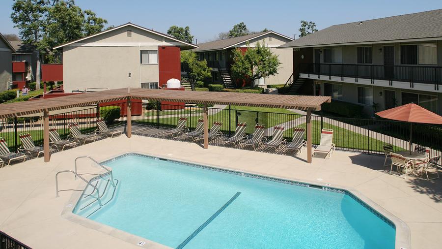 a swimming pool surrounded by lawn chairs and umbrellas.
