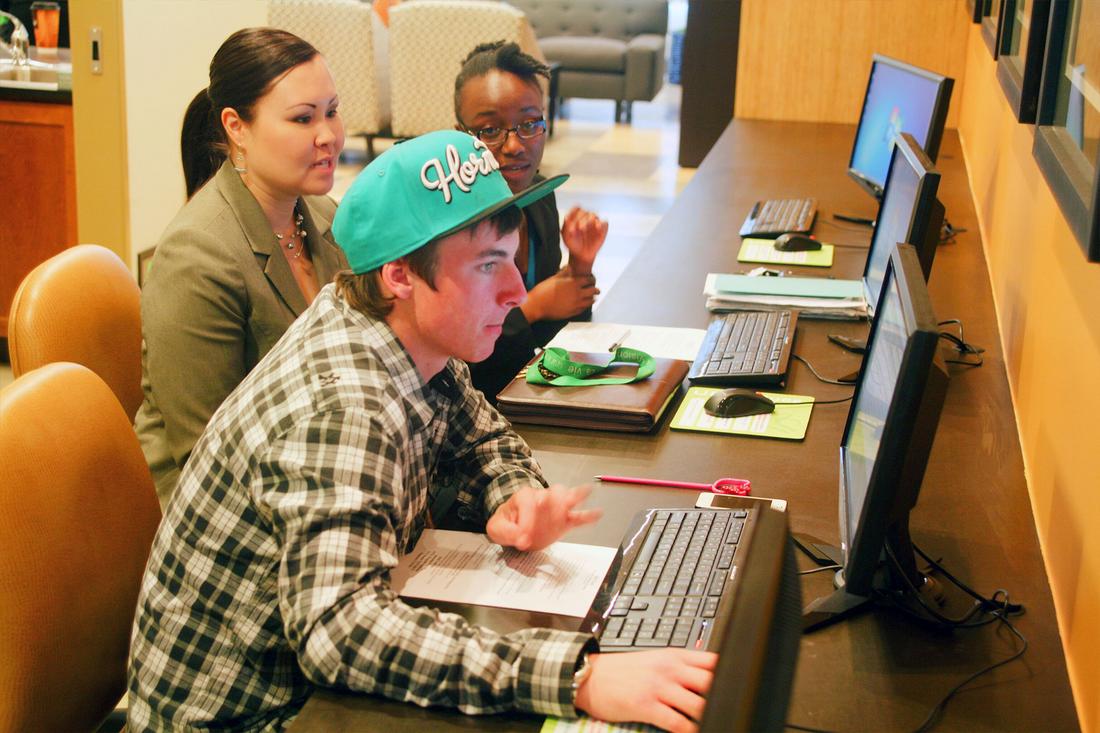 a group of people sitting around a computer.