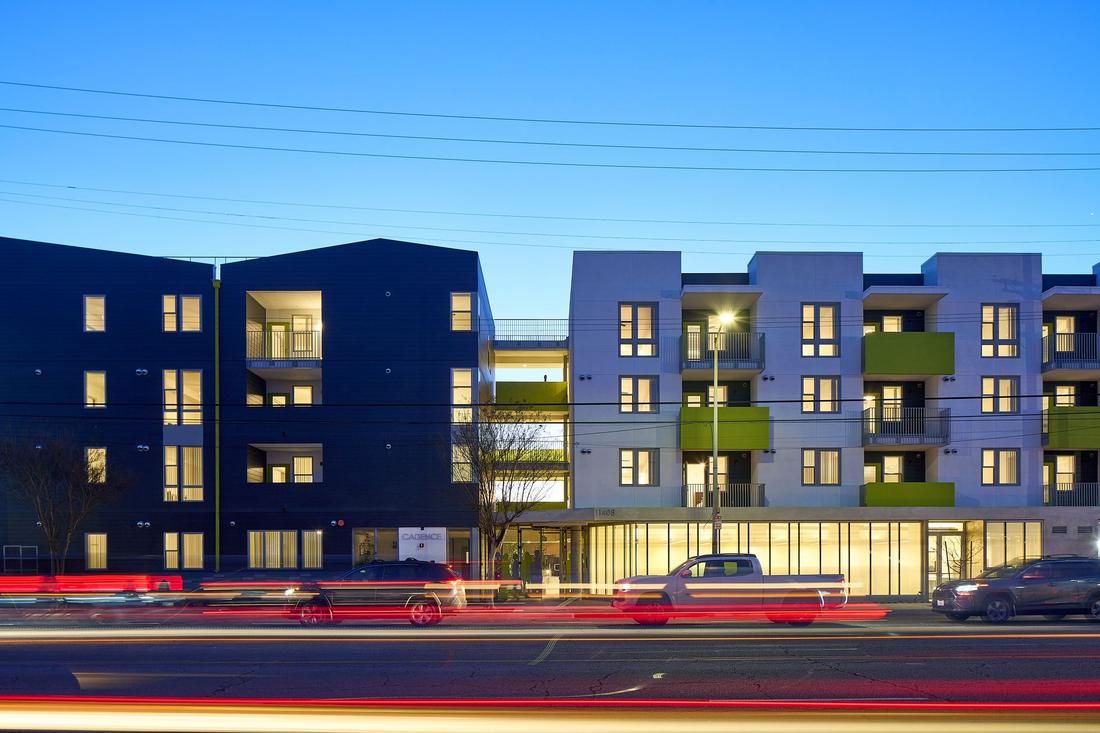 a street with cars driving past a multi - story building.