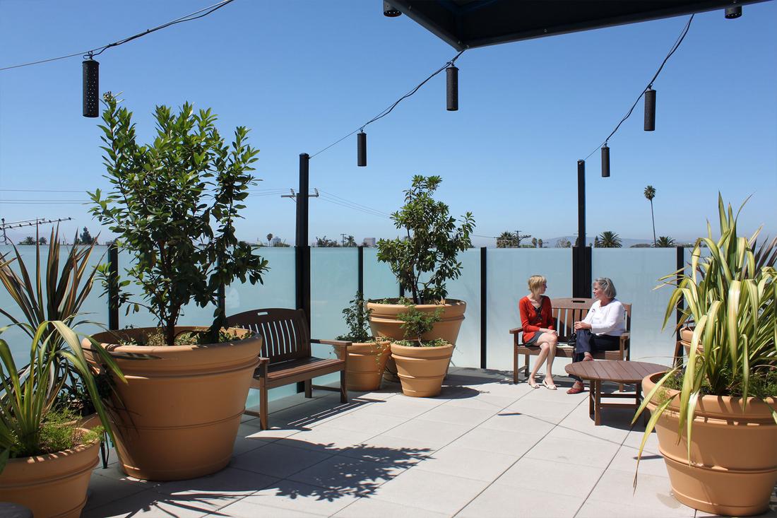 a woman sitting on a bench next to a couple of potted plants.